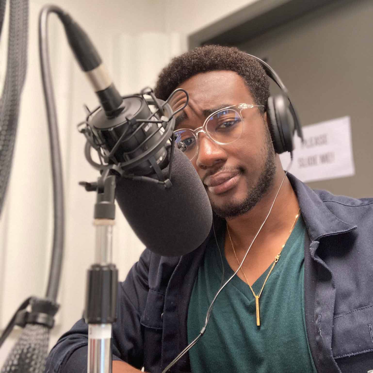 Portrait of Kafui Okpattah, wearing headphones and with a radio microphone in the foreground