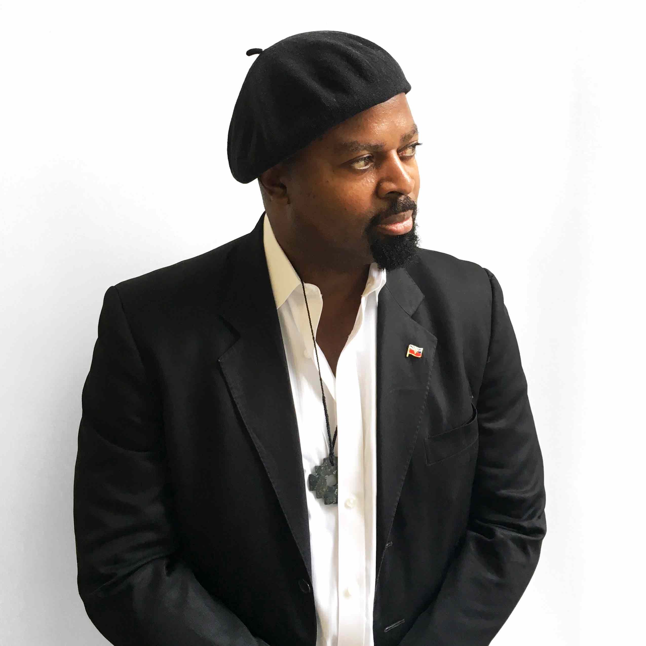 Ben Okri, wearing a black jacket, white shirt and black beret.