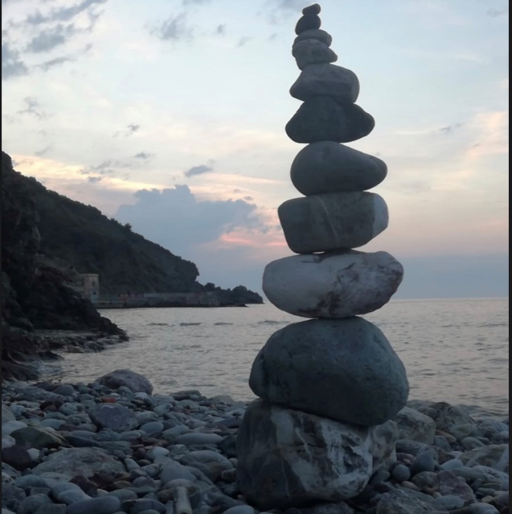 photograph of coast scene with tower of stones against evening sky