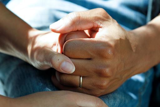 close up of two people holding hands in a care setting