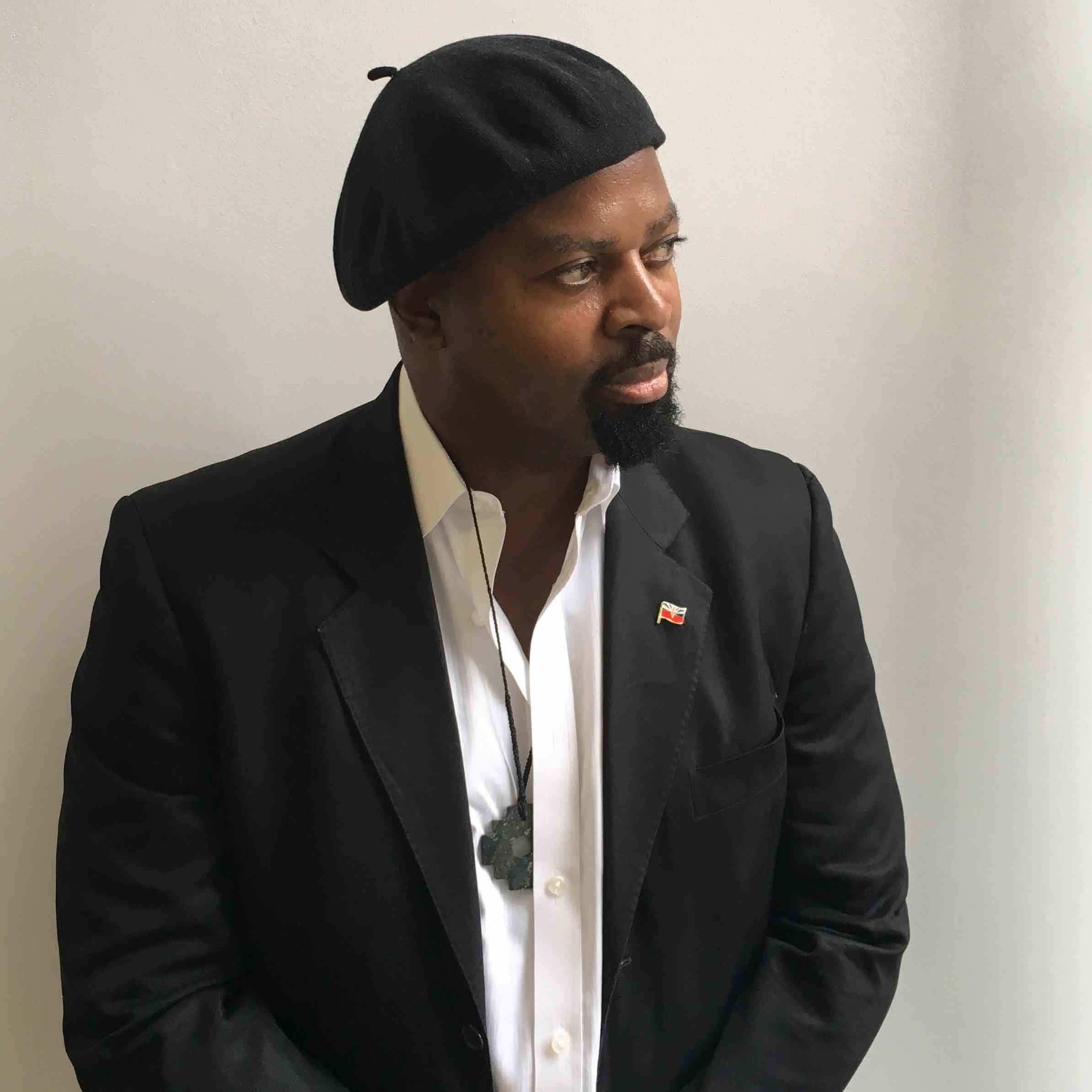 Ben Okri, wearing a black jacket, white shirt and black beret.