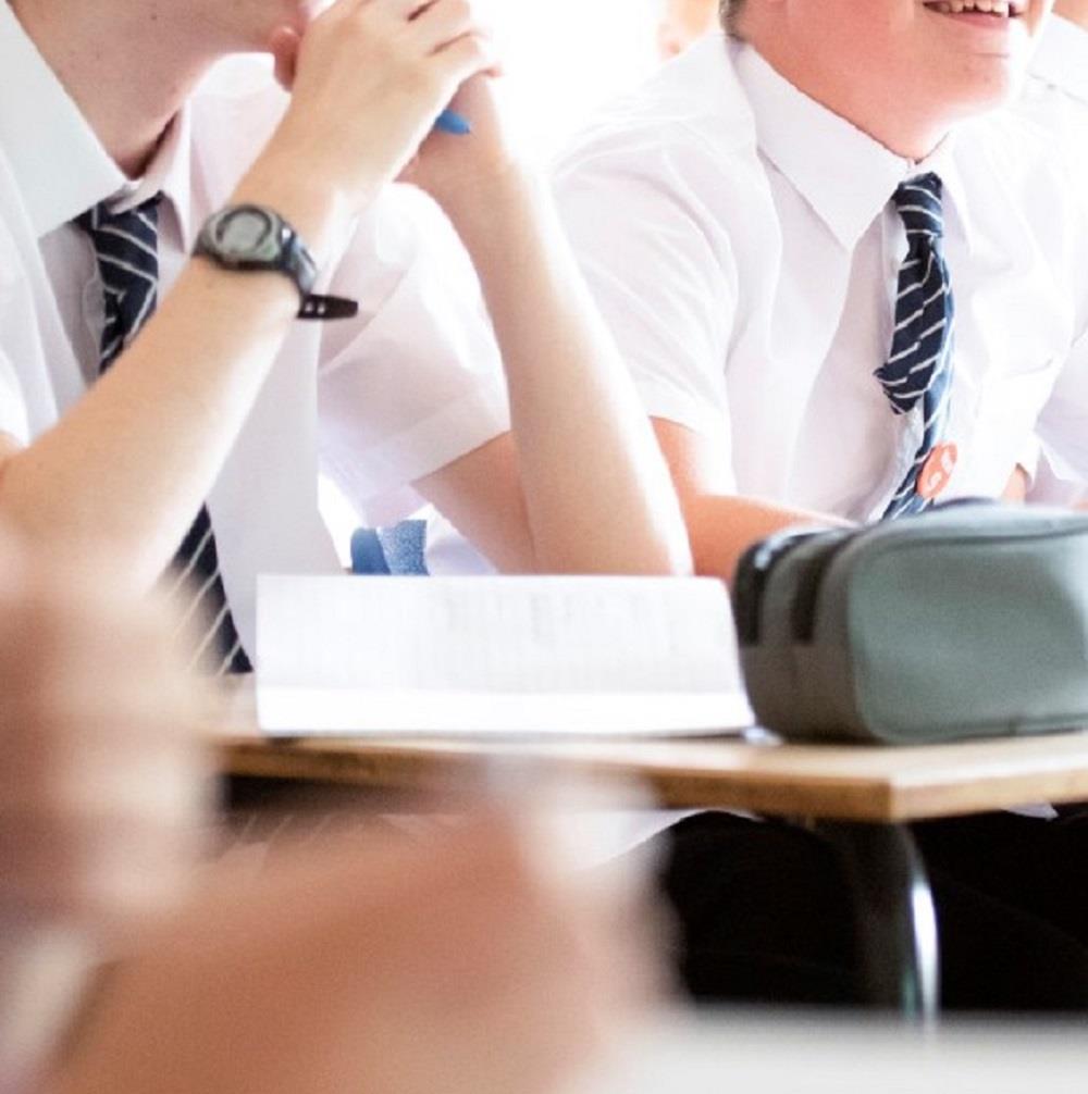 close up of unidentified school boys in school uniform at desk 