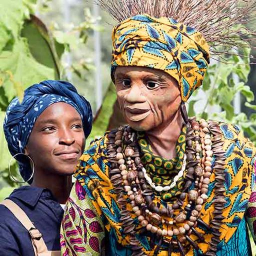 A Theatre Rites actor with a puppet, both wearing African-inspired costume