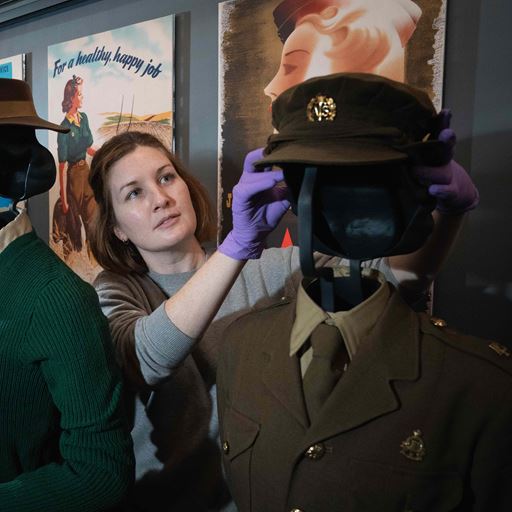 A curator adjusts the hat on a mannequin, dressed as a British soldier, in the Imperial War Museum.