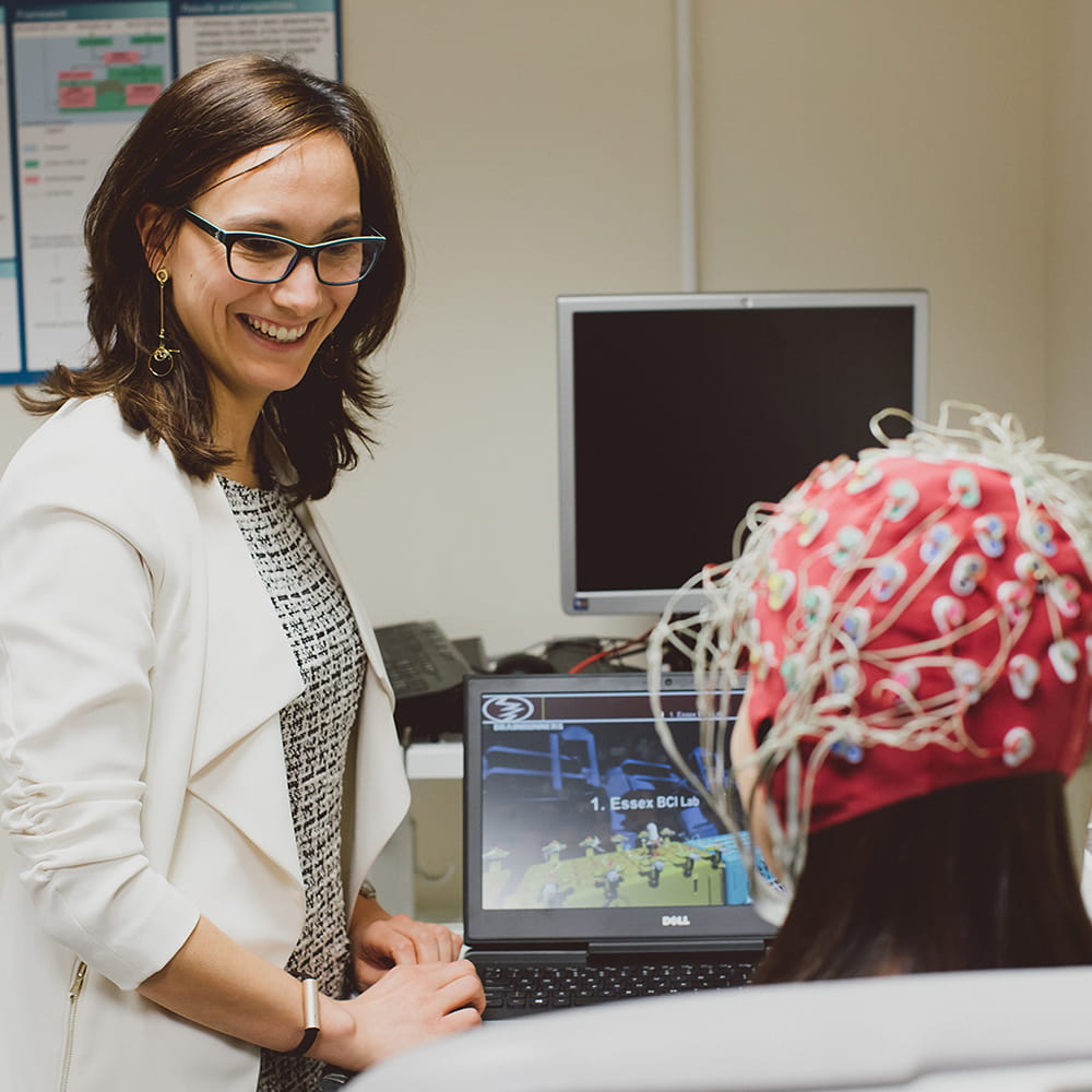 Female student using brain mapping technology with volunteer