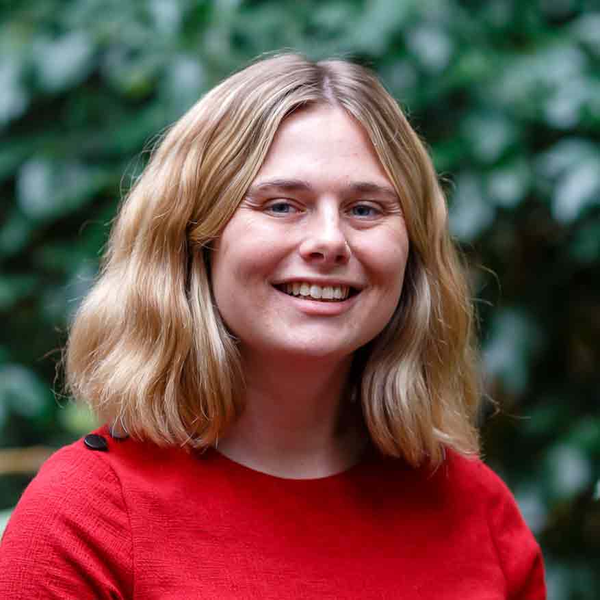 Natasha Richards, smiling at the camera with green foliage behind