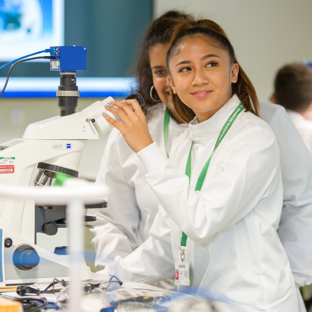 students in lab coats with microscope