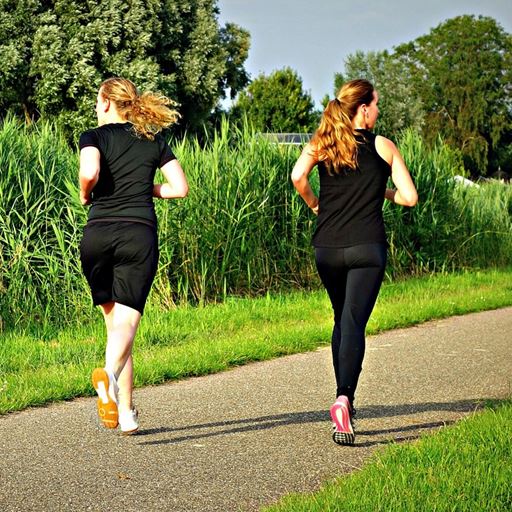 Two women jogging through green space
