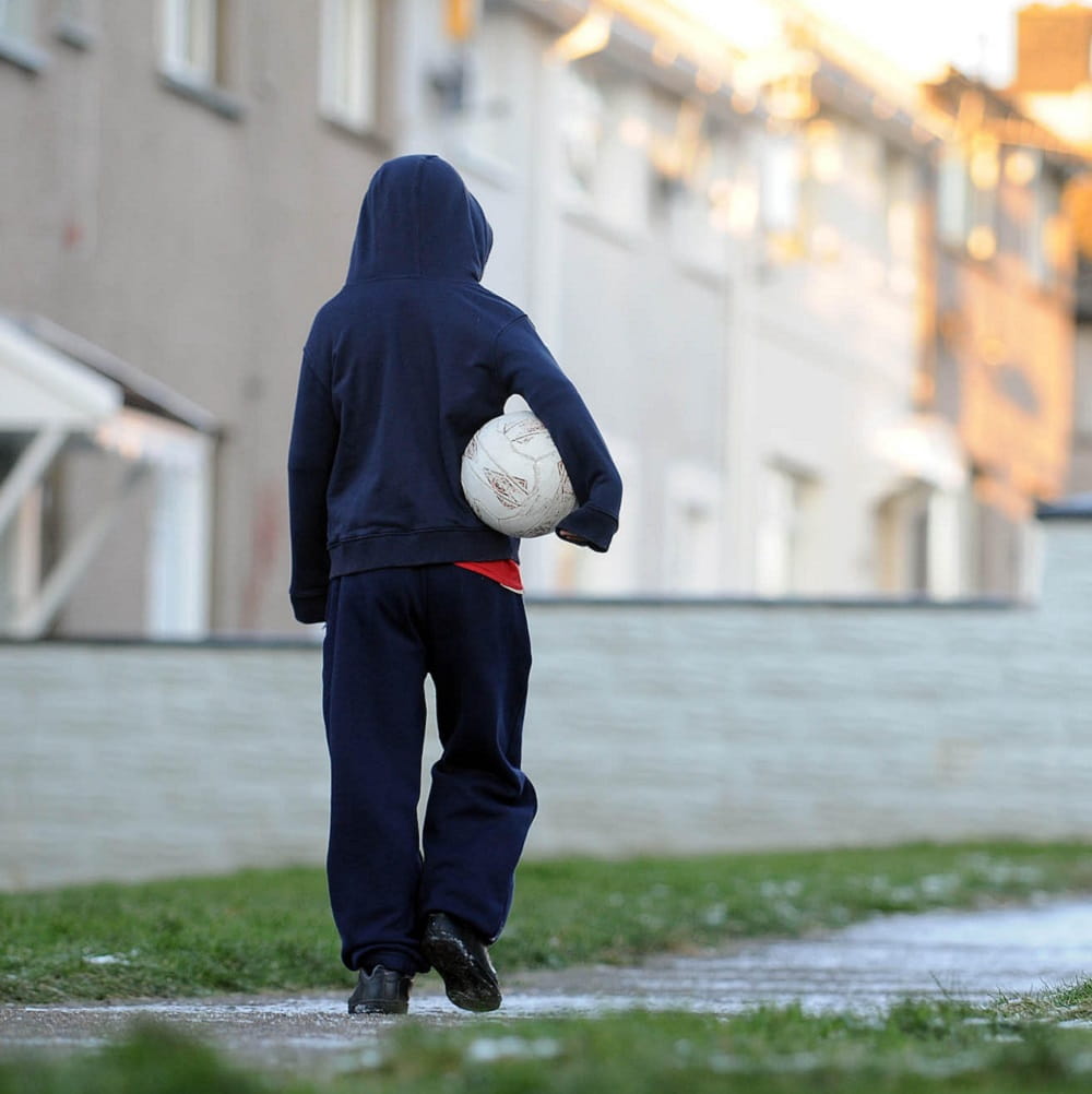 Child walking with football in hand