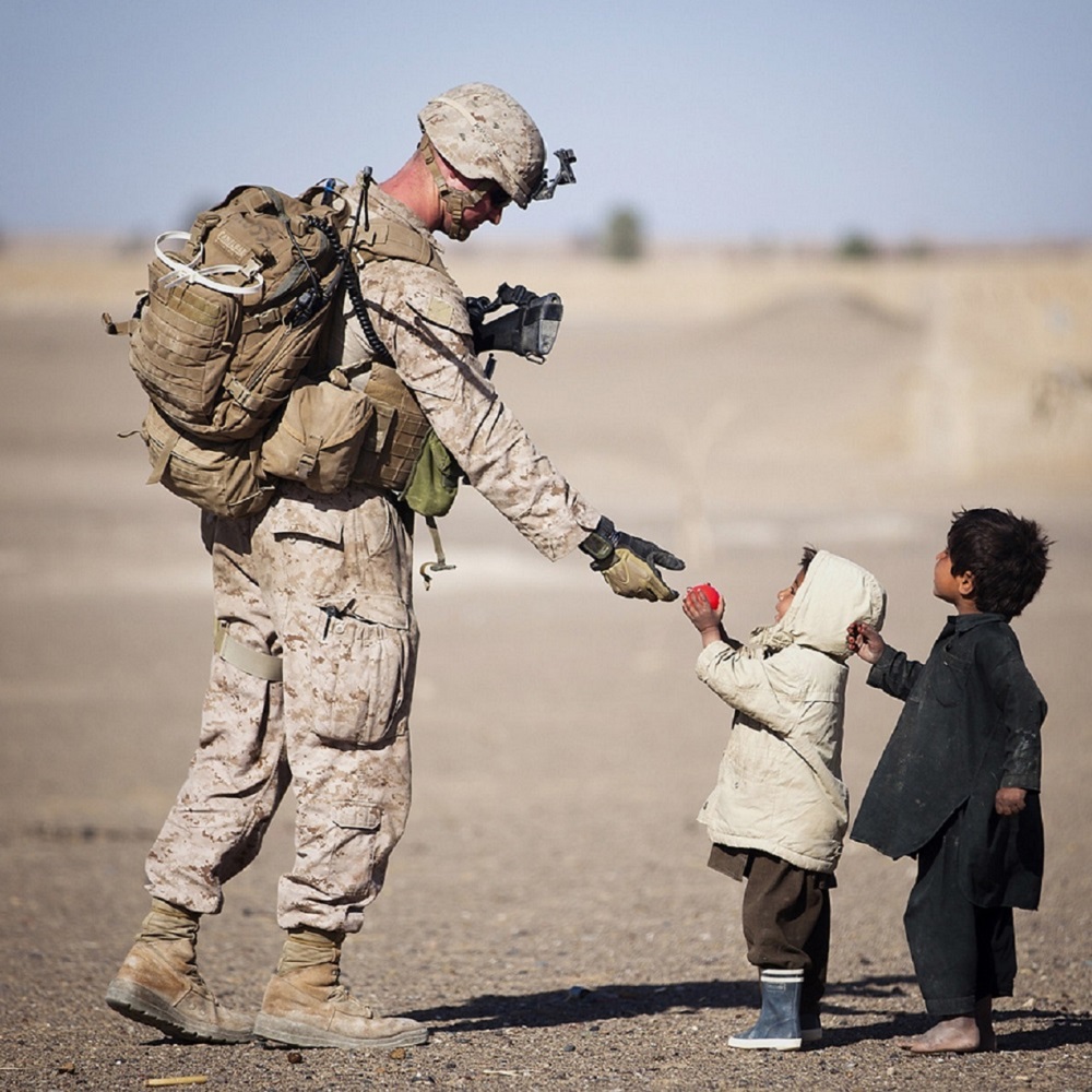 international relations conflict war army soldier gives aid to two young children