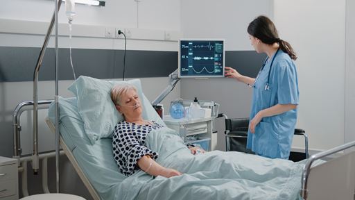 adult in hospital bed with nurse attending