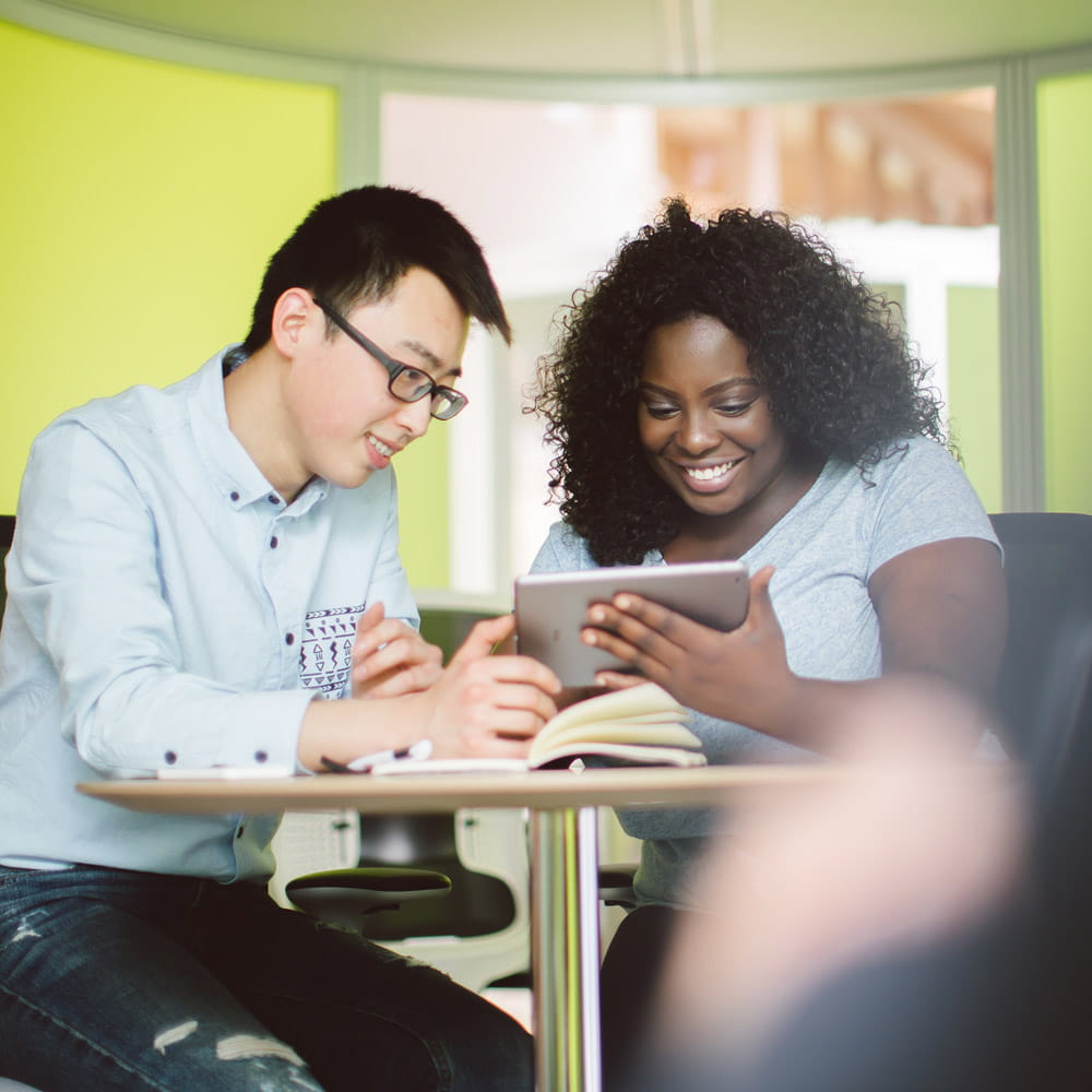 Male and female student looking at a tablet