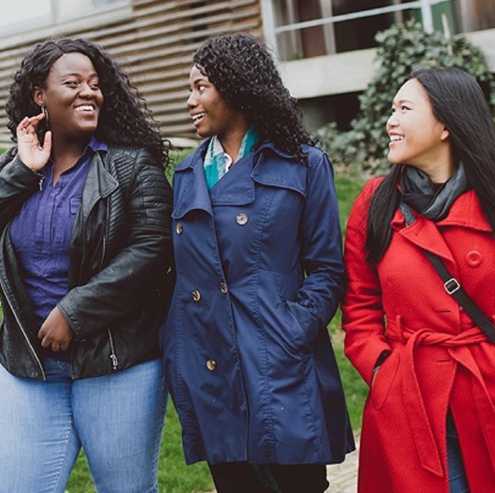 Three female BAME students laughing and talking together
