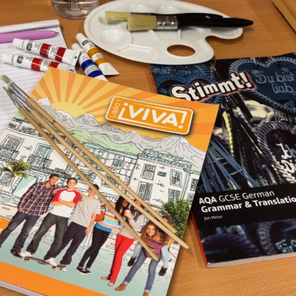 Image of two language text books, paintbrushes, art palette and paints
