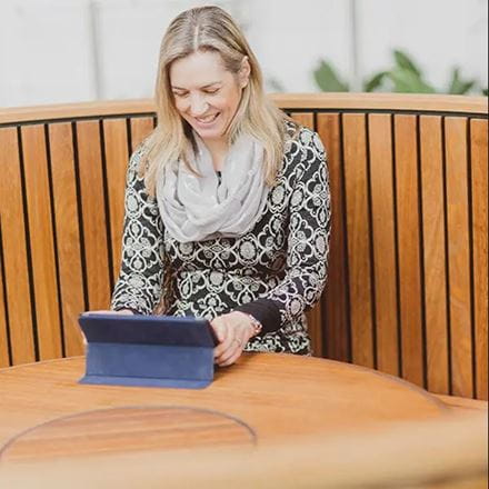 a female mature student sitting at a round table using an ipad