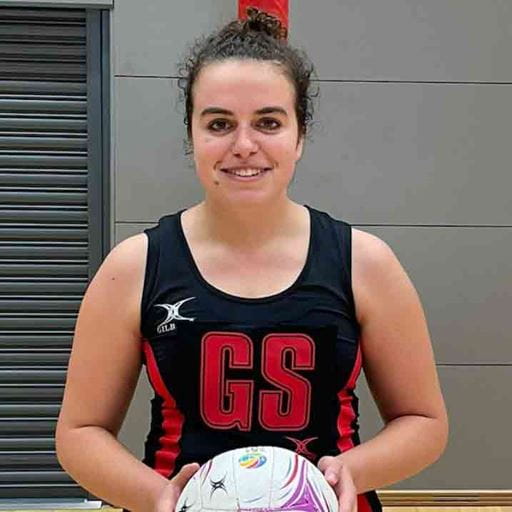 Elsa Philbedge wearing her Essex Blades netball kit, smiling and holding a netball