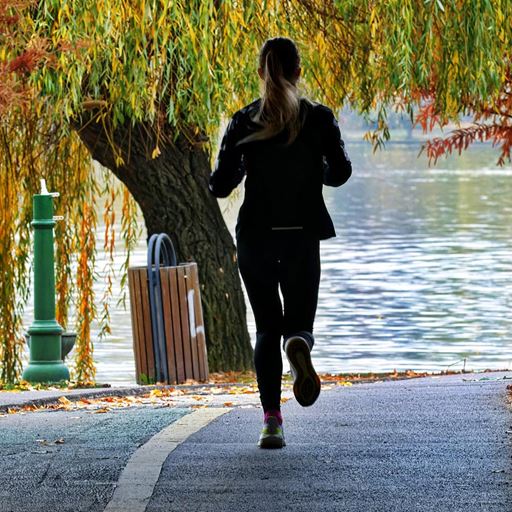Woman jogging down a path by a lake