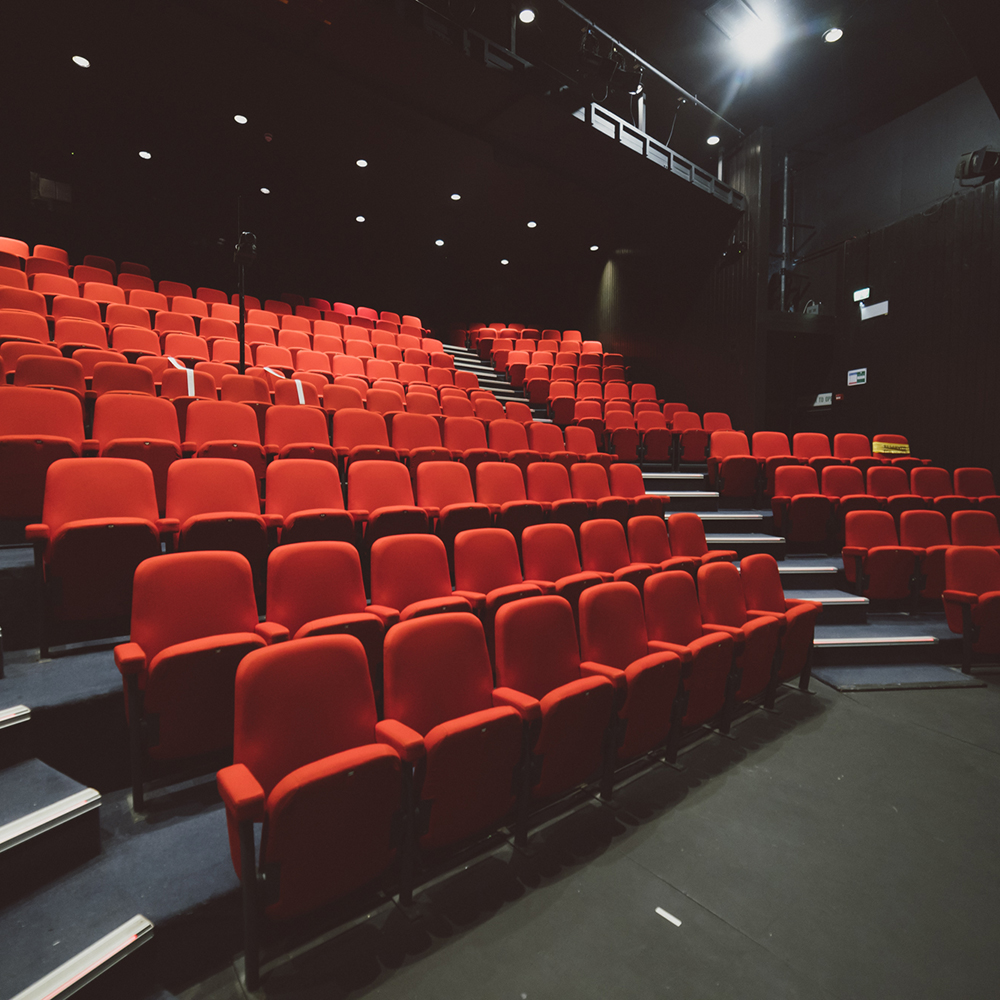An inside shot of the Lakeside Theatre main stage seating. The seating is red against the black walls and ceiling of this underground theatre.