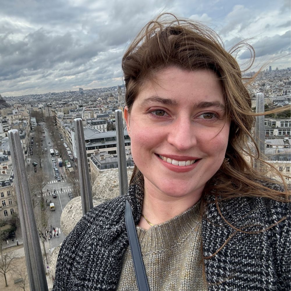 Sarai Lambert standing on a tall building in Paris which overlooks the Eiffel Tower