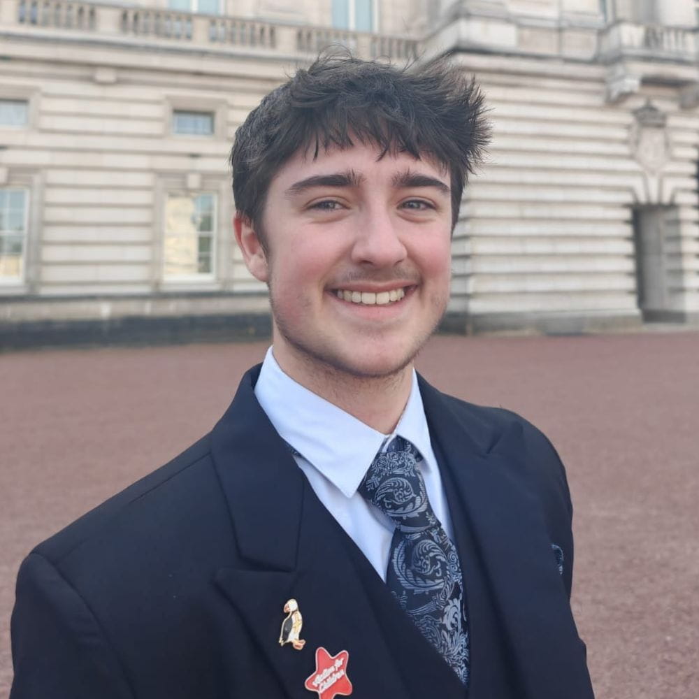 Charlie Murray-Edwards, smiling, outside Buckingham Paalce