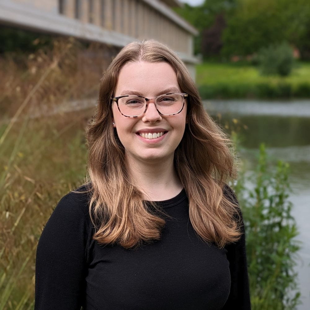 Angelia Harvey, standing in front of a lake, smiling