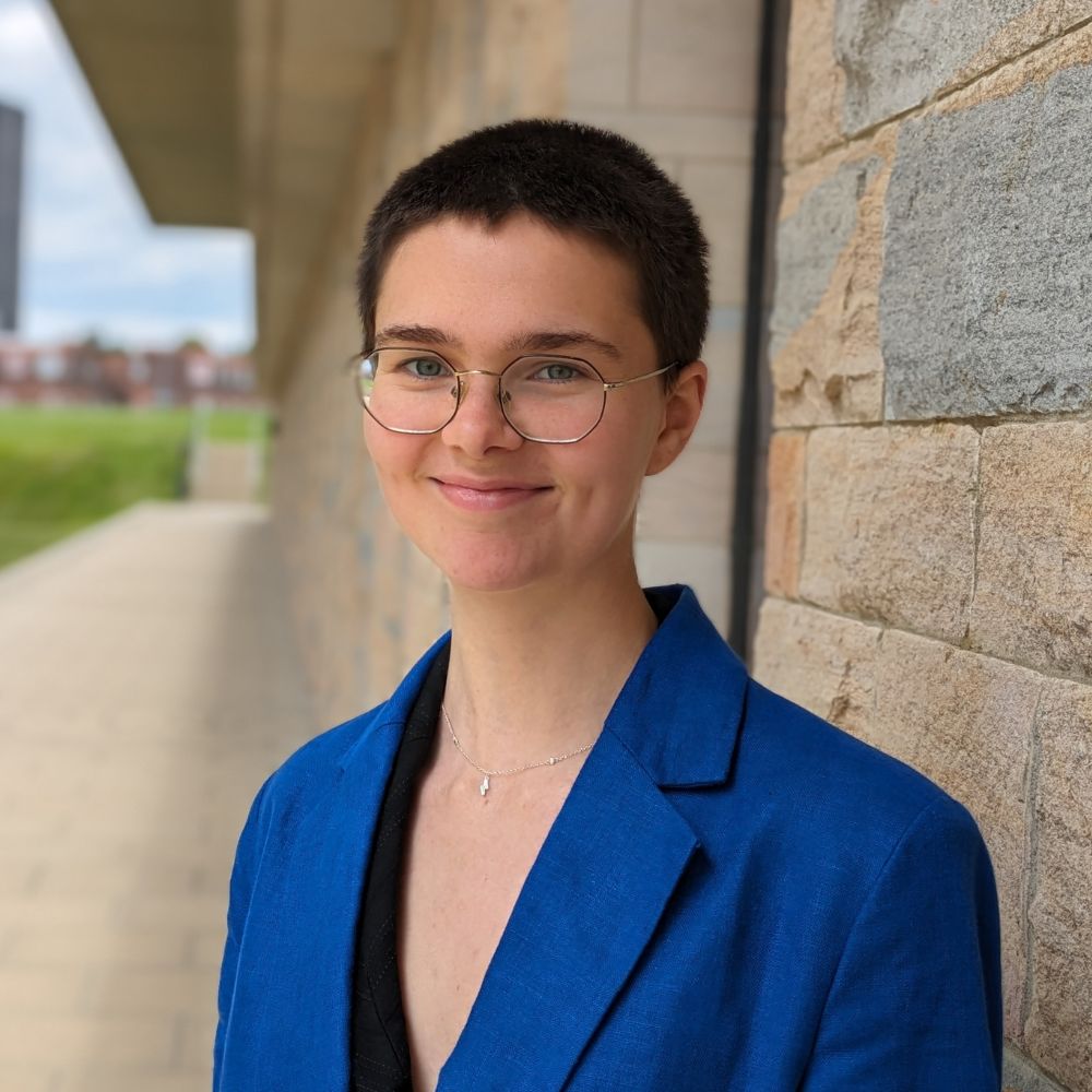 Gemma Smith, wearing glasses and a vibrant jacket smiling