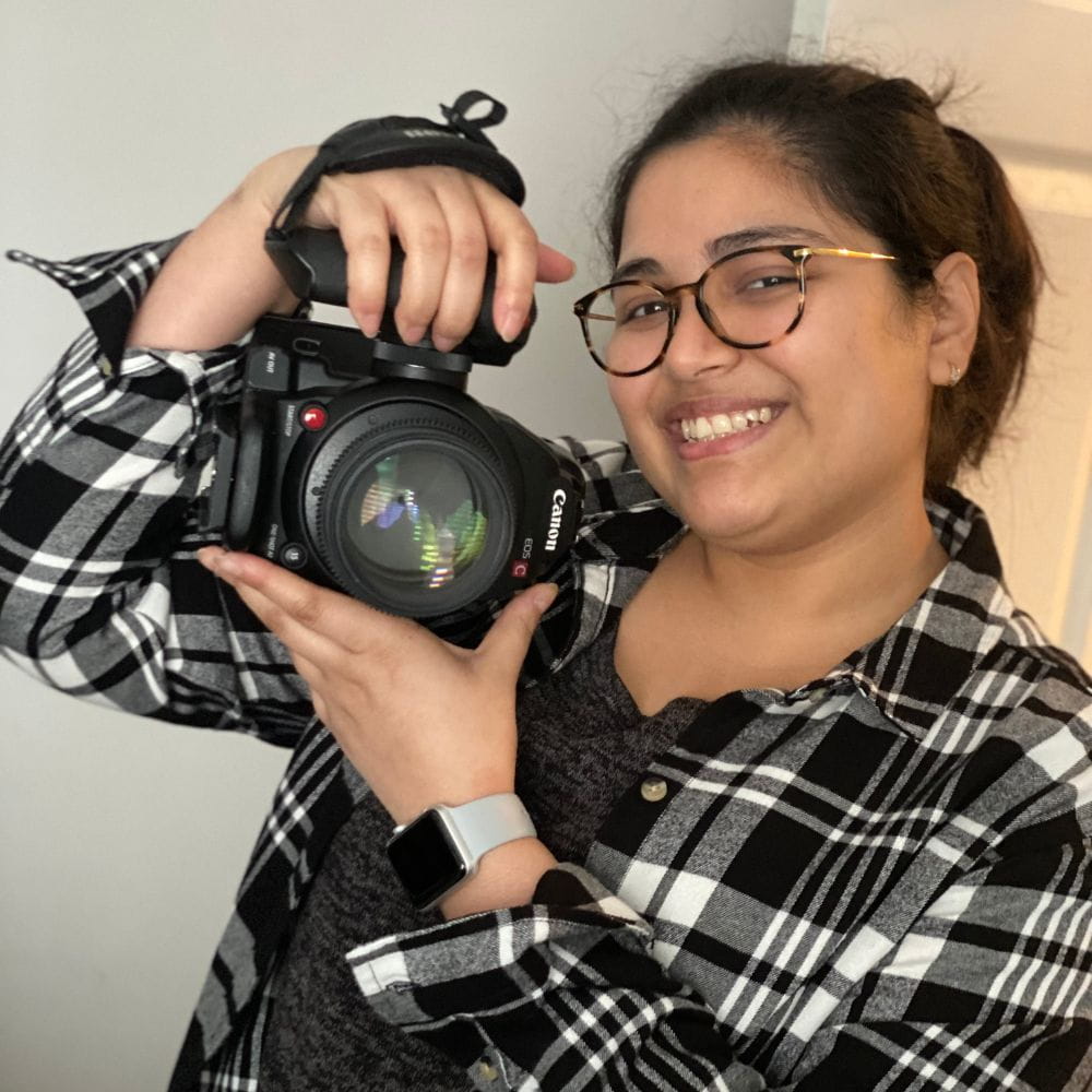 Koushiki Chowdhury, smiling an holding up a camera