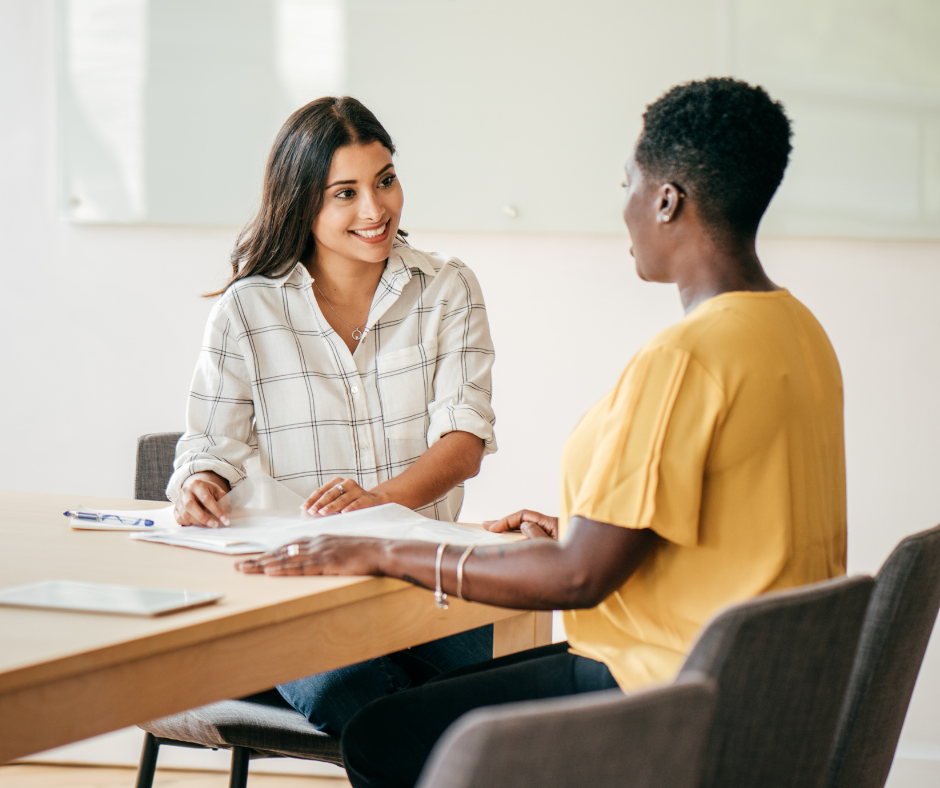 two people sitting at a desk talking to one another