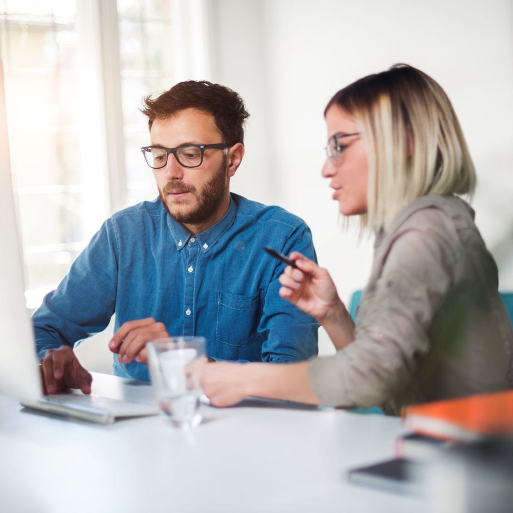 Two people at desk looking at laptop