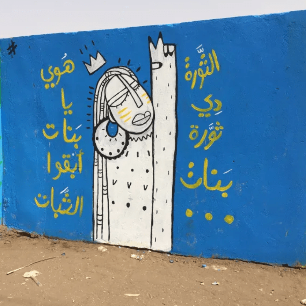 wall painted blue with an illustration of a woman using a peace sign and yellow text around the edge