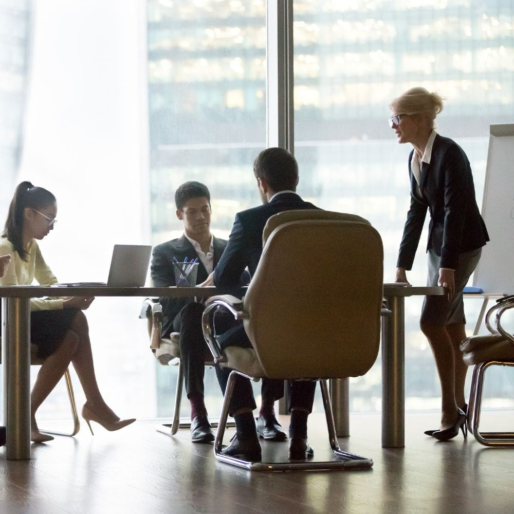 Office workers sitting and standing around a table