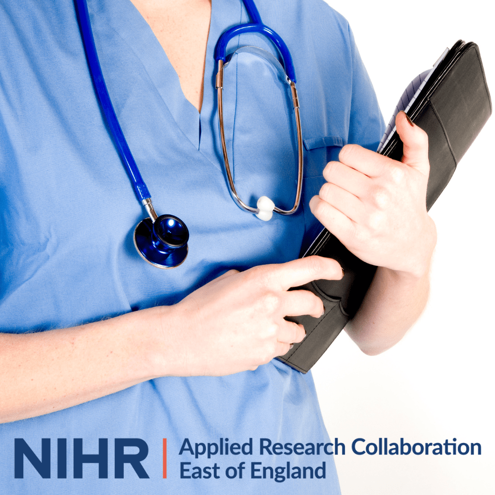 A healthcare working holding a notebook while wearing blue scrubs