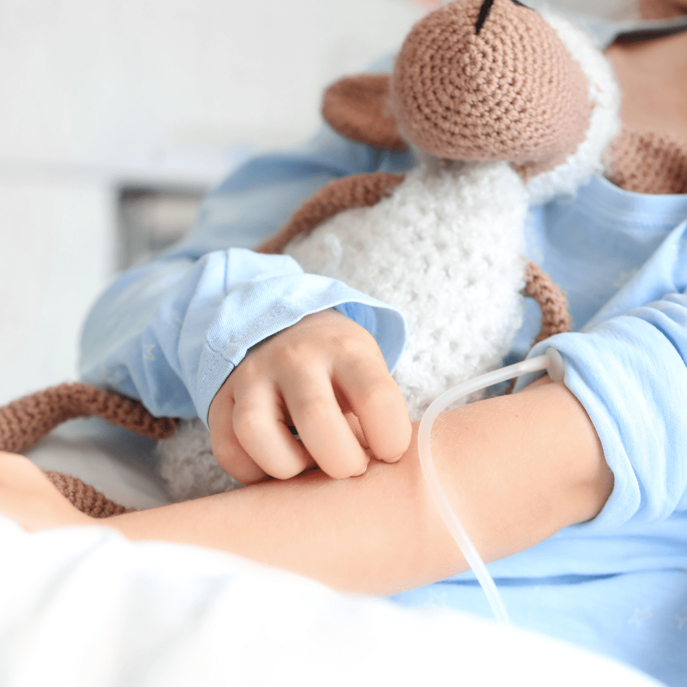A child in a hospital bed holding a soft toy