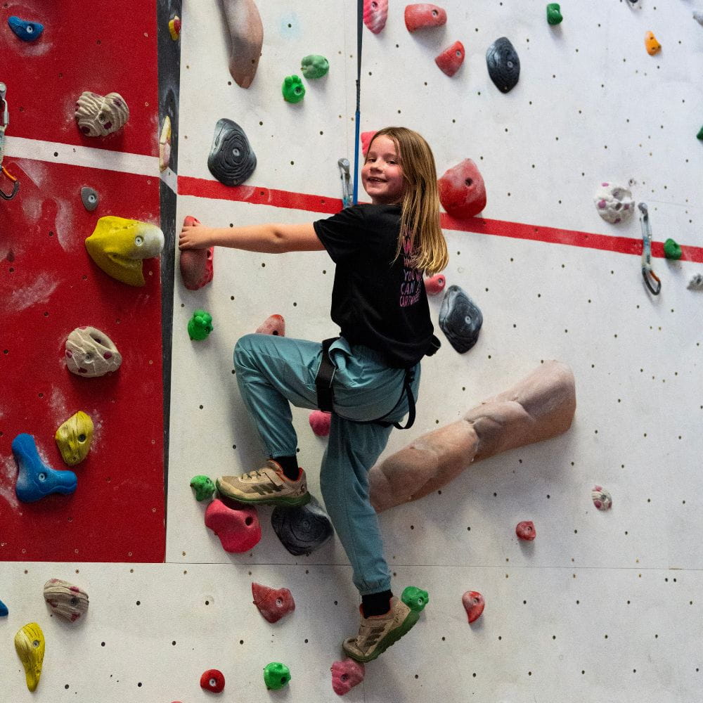 A kid enjoys the climbing wall