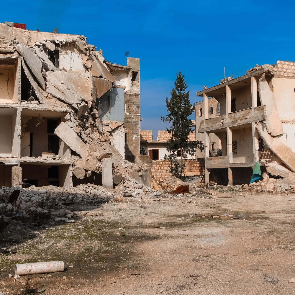 Damaged three-storey buildings on a dusty street 