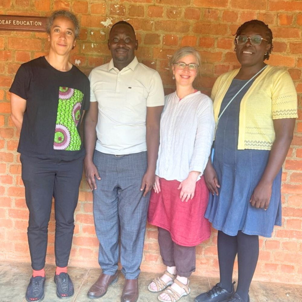 Professor Hannah Gibson, Dr Sam Lutalo-Kiingi, Dr Hope Morgan and Margaret Odhiambo standing by brick wall in Uganda