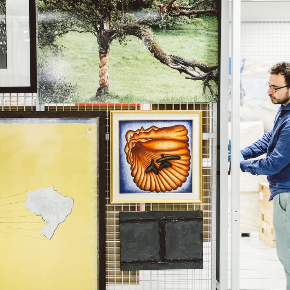Male student in Art Exchange gallery placing artwork on the wall