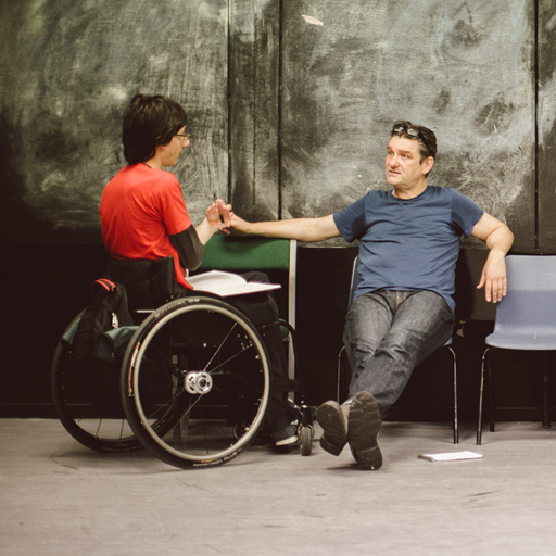 A student in a wheelchair talking to another person who is seated. 