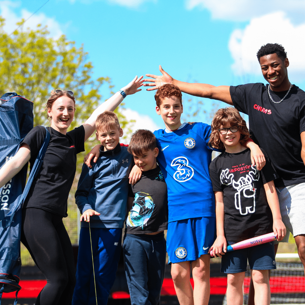 Group photo of fours kids and two coaches outside on a sunny day