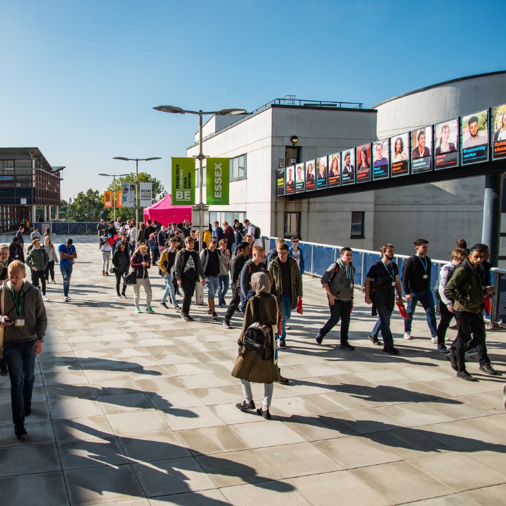 Students walkthrough a sunlit Colchester campus 