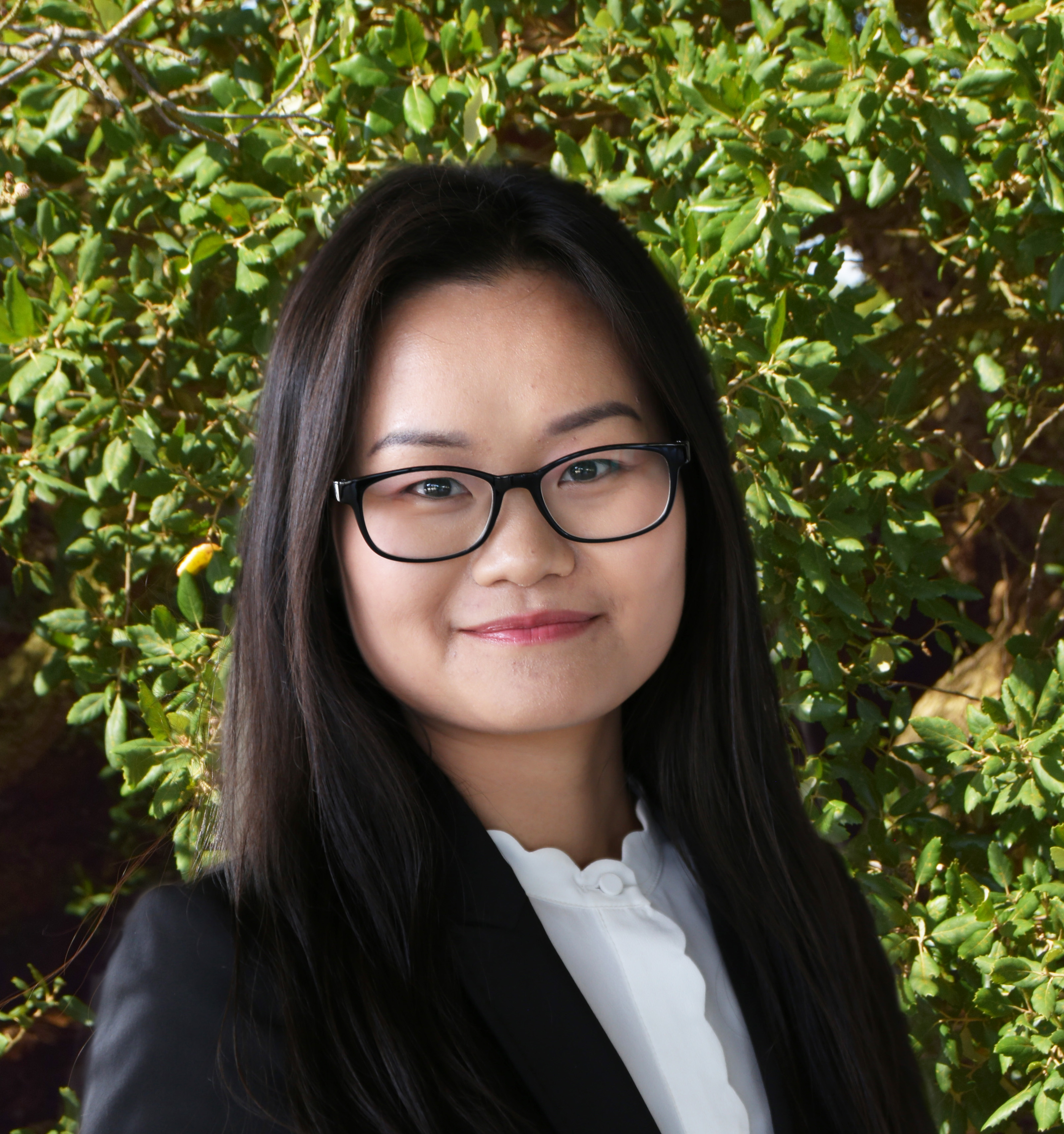 Quynh Nguyen stands in front of a foliage background