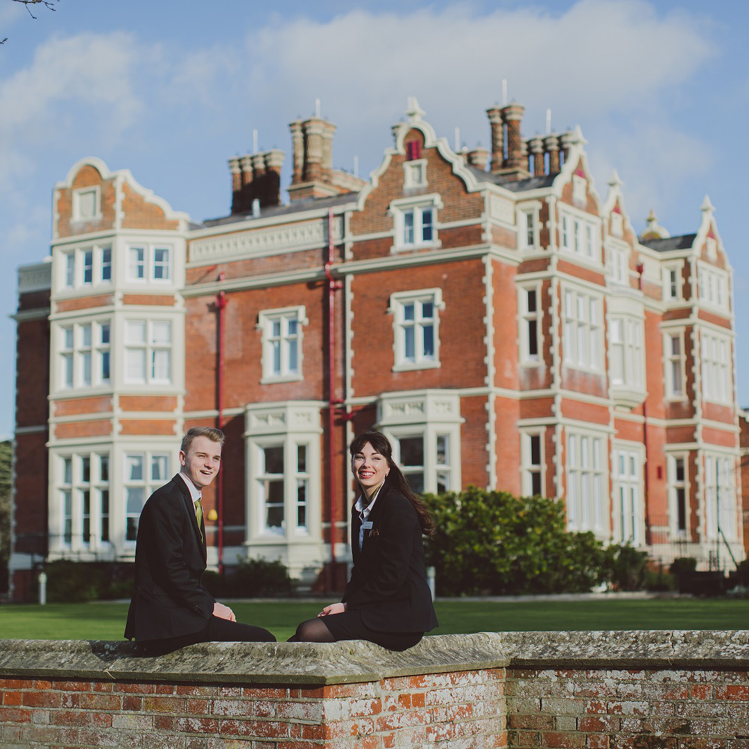 Students sitting in front of Wivenhoe House hotel