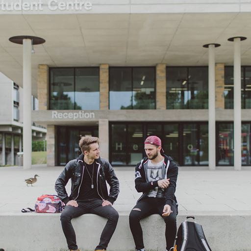 Two male students sitting outside the Silberrad Student Centre
