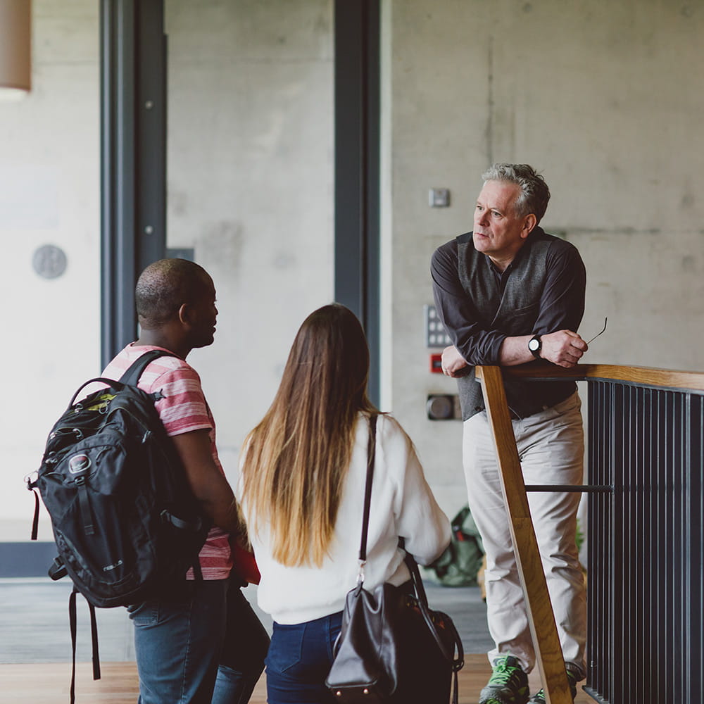 Male and female student talking to a male academic