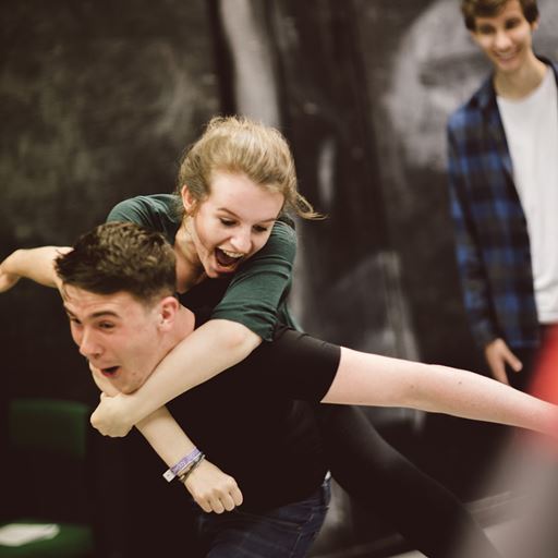 Female student jumping on the back of male student in a drama class