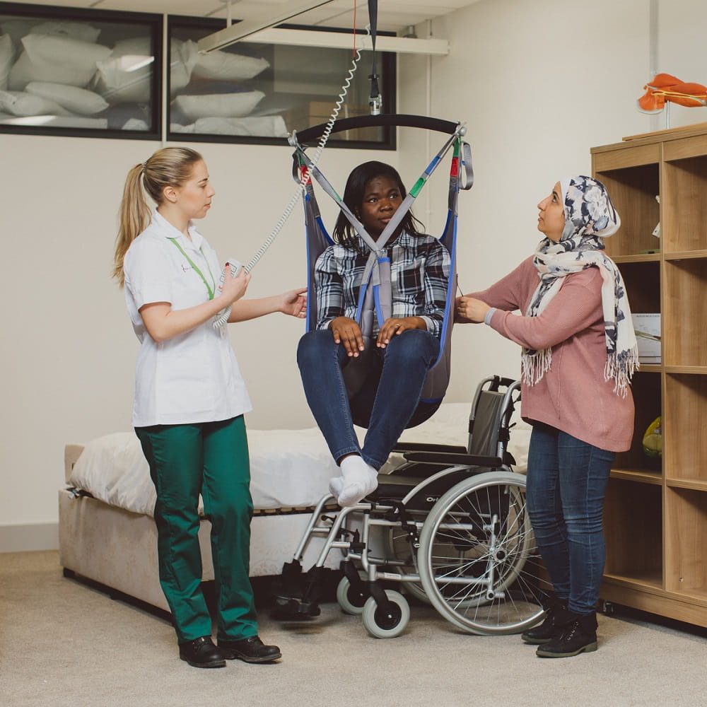 Two educators demonstrating a mechanical hoist with a student.