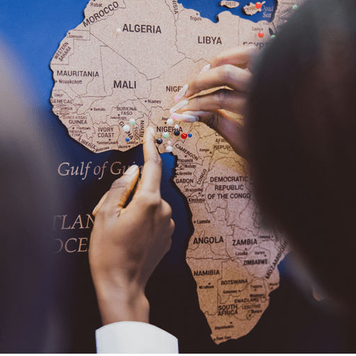 A world map pinboard showing students putting a pin in Nigeria