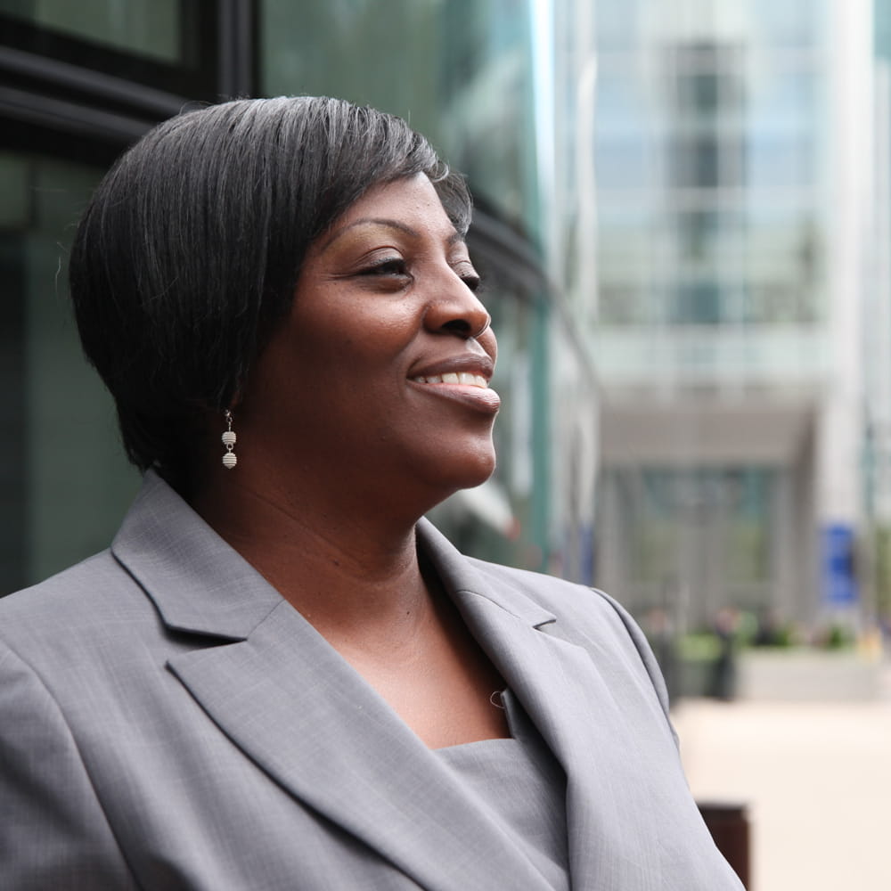 Lady in suit pictured against a backdrop of city buildings 