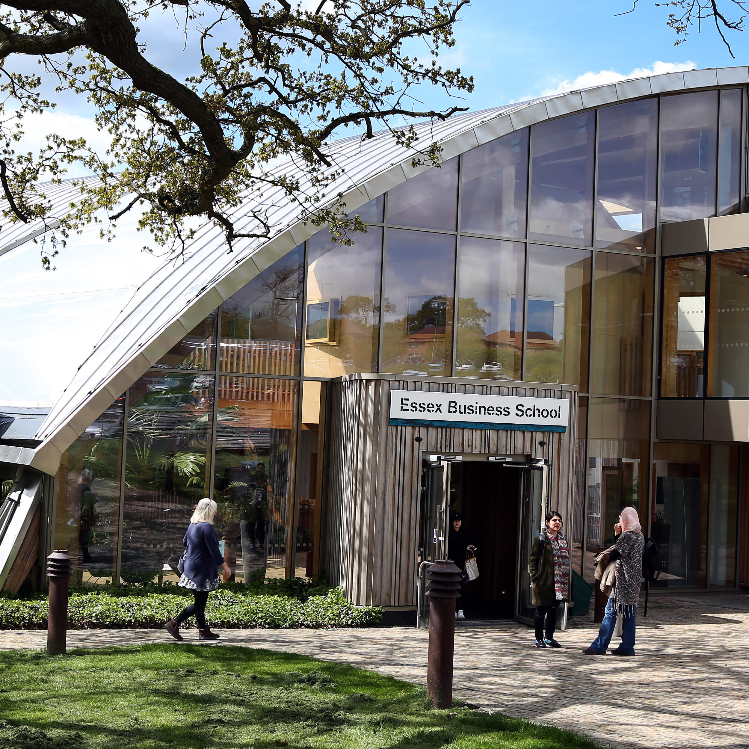 The front facade of Essex Business School on a sunny day with women talking to one another stood outside