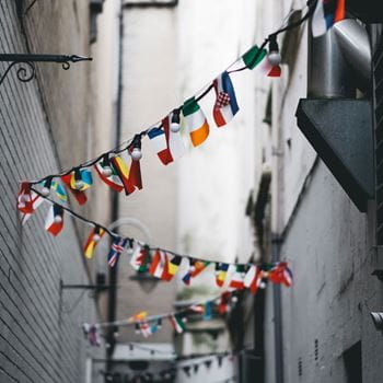 A string of flags criss-crossing between the walls of two buildings.